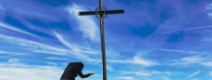 woman kneeling facing the cross and how to ask god for forgiveness
