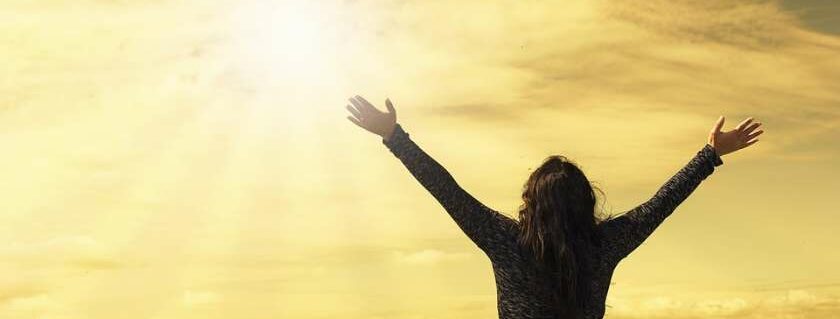 woman praising with hands raised on mountain top and power of god