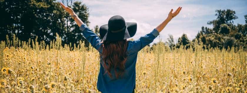 woman raising hands on sunflower field and god is gracious