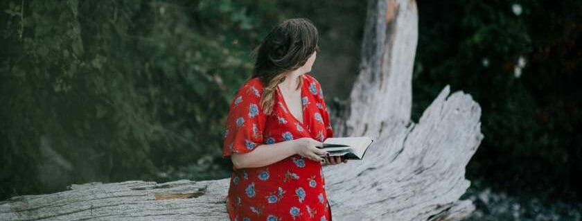 lady in red dress holding a bible and sitting on tree log and women of god