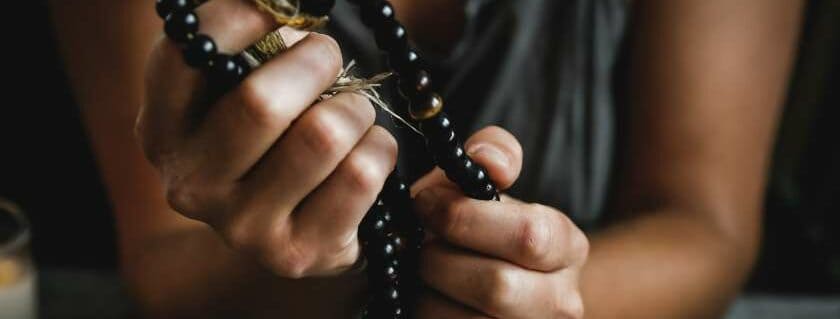 woman holding black rosary and apostles creed prayer
