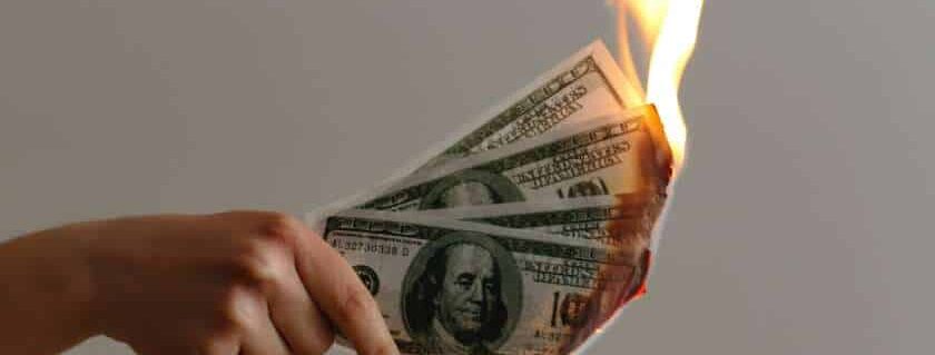 hand holding burning money and you cannot serve god and mammon