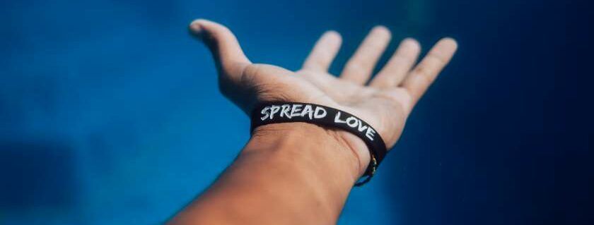 hand wearing spread love wrist band and sharing the love of god