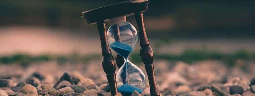 hourglass on rocks sand and god is always on time