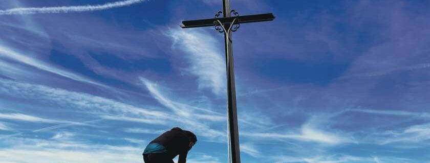 woman person kneeling praying by the cross