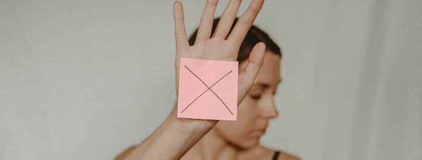 woman with her face turned away and an x on her hand