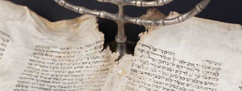torn page with ancient text against silver menorah