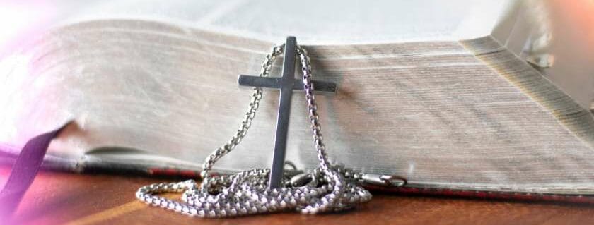 cross with a chain next to an open bible