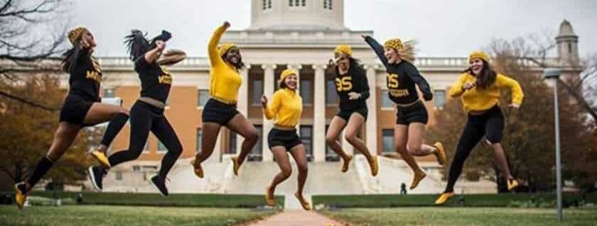 group of female athletes jumping against bakcground of christian college in missouri