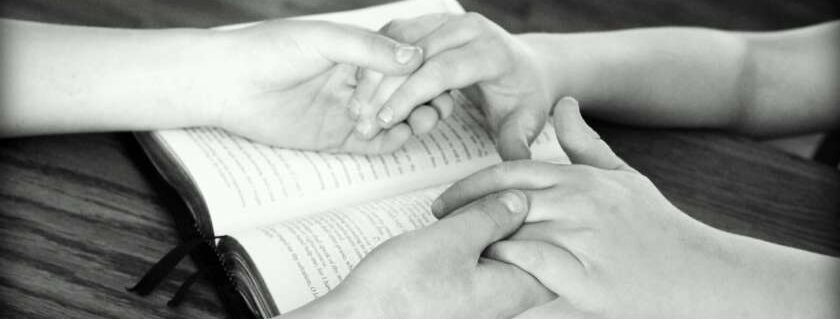 two set of hands holding each other on top of a bible
