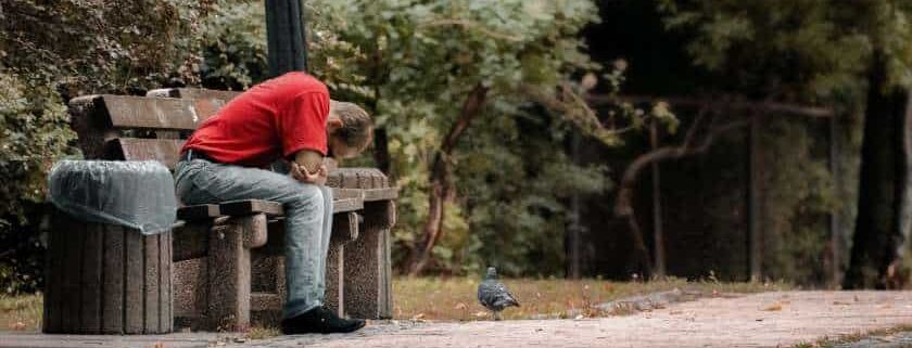 man sitting on bench in sorrow