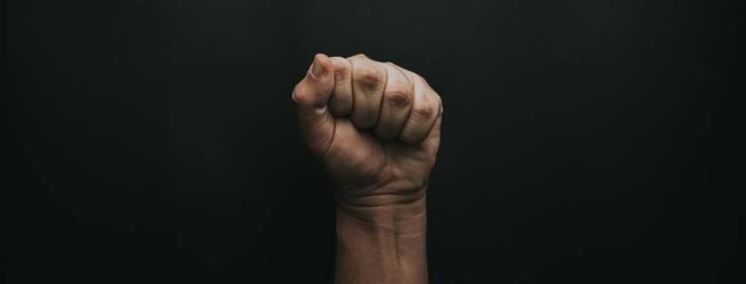 fist raised in the air against dark background and contend for the faith