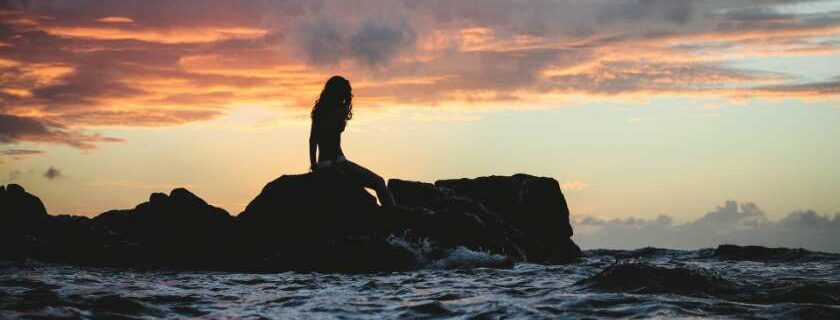 woman sitting on a rock above ocean waves and contend for the faith